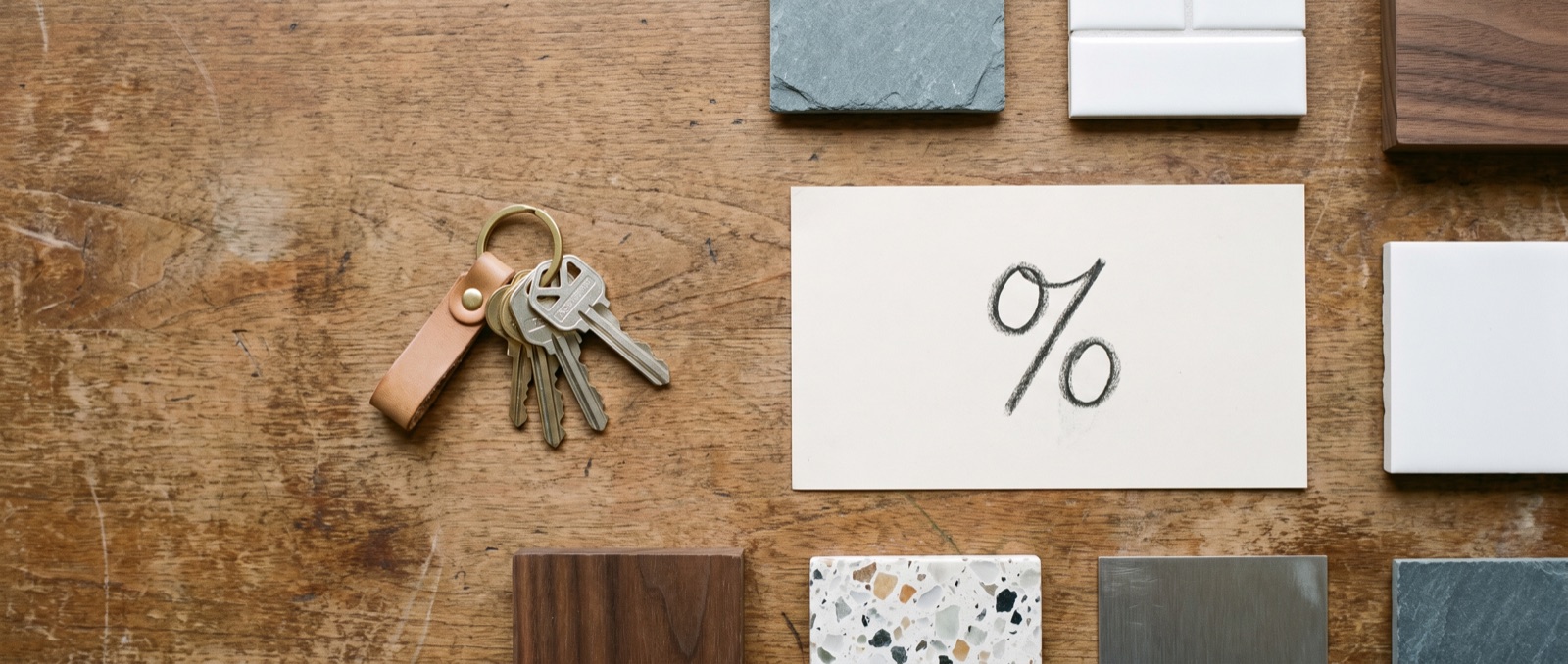House keys, kitchen finish material swatches, and a percentage rate symbol on a desk