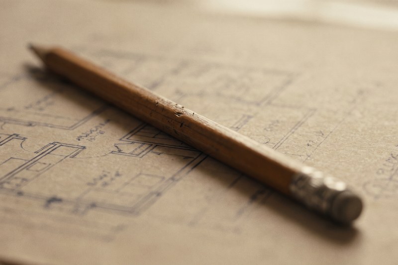 A hand-drawn floor plan on a table with a pencil