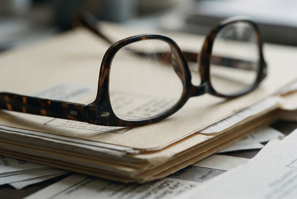 Reading glasses resting on a stack of document folders