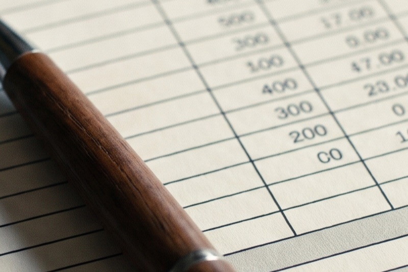 A builder price sheet with a tax line, calculator, and pen on a desk