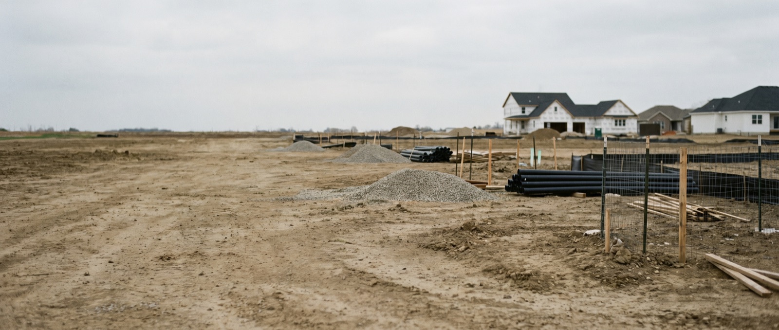 A vacant new-construction lot with surveyor stakes in a suburban Edmonton subdivision