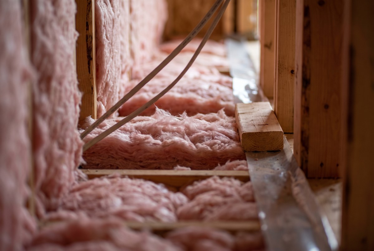 Exposed insulation and framing in a new-construction wall cavity before drywall