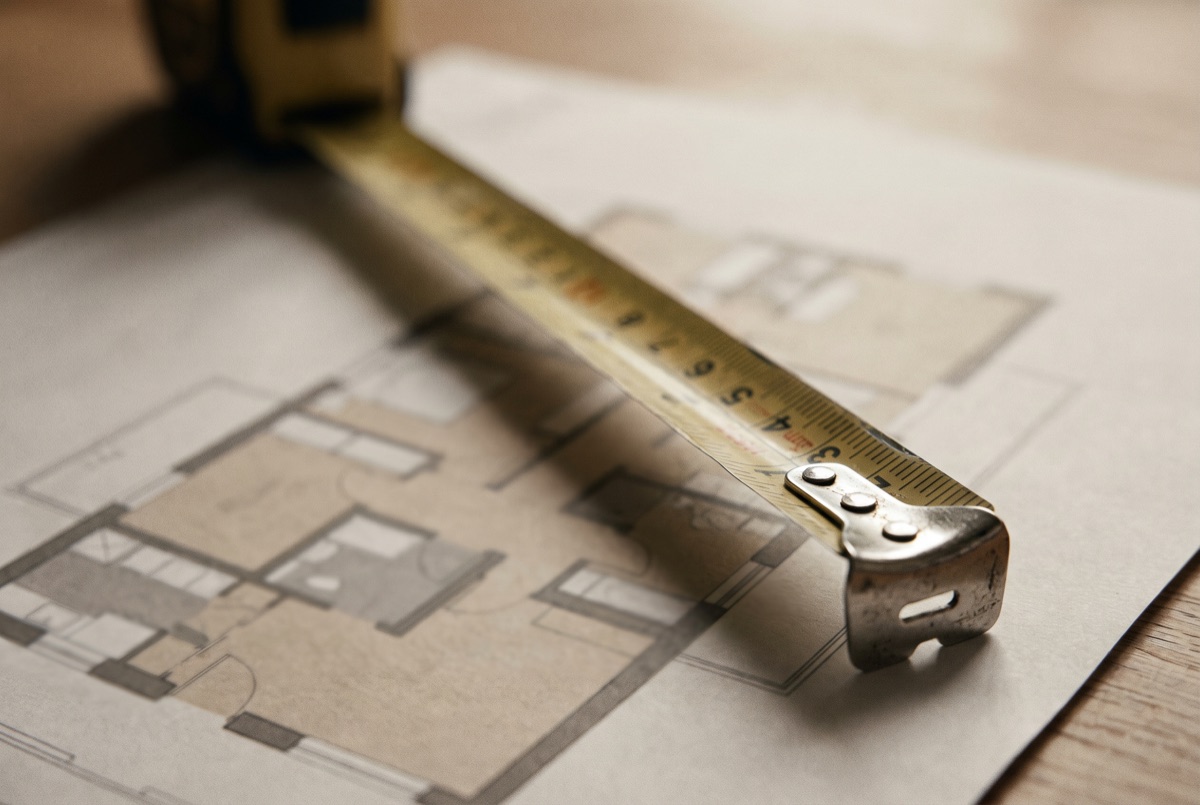 A tape measure resting on a house floor plan