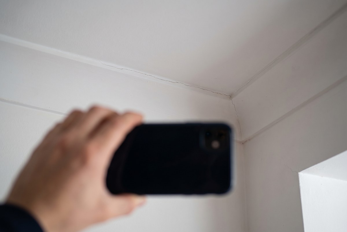 A close-up of a phone camera photographing a small ceiling crack